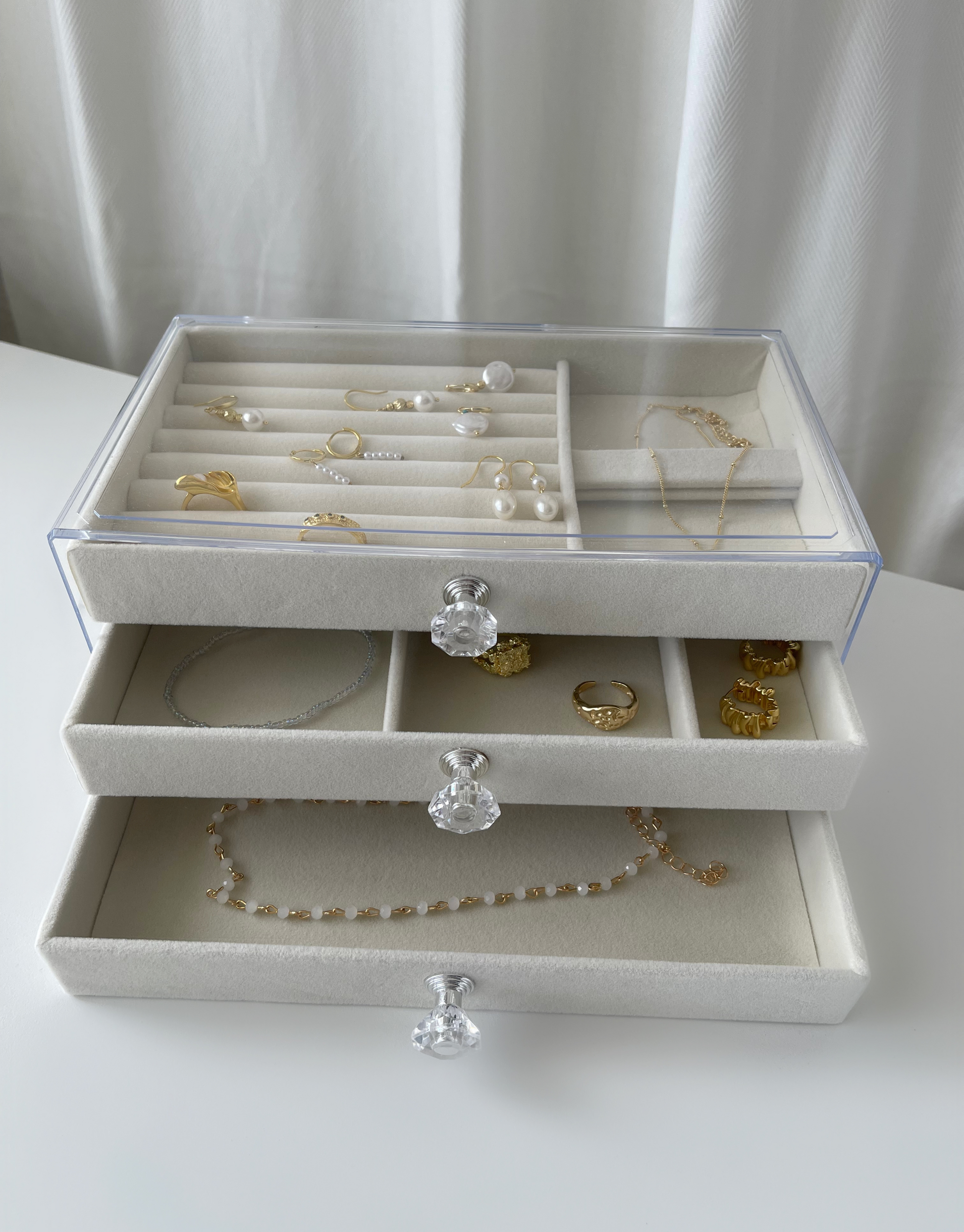 Smukt beige smykkeskrin i akryl med 3 skuffer.  Specifikationer: Materiale: Akryl Mål: 18 x 15 x 27 cm Farve: Beige