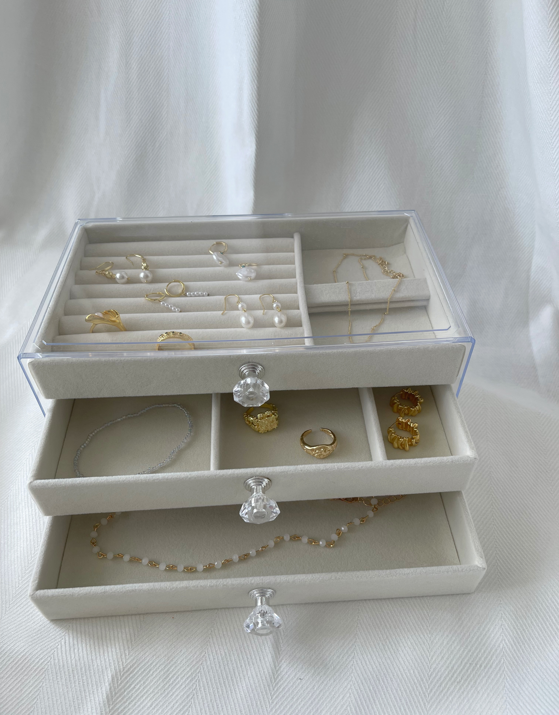 Smukt beige smykkeskrin i akryl med 3 skuffer.  Specifikationer: Materiale: Akryl Mål: 18 x 15 x 27 cm Farve: Beige