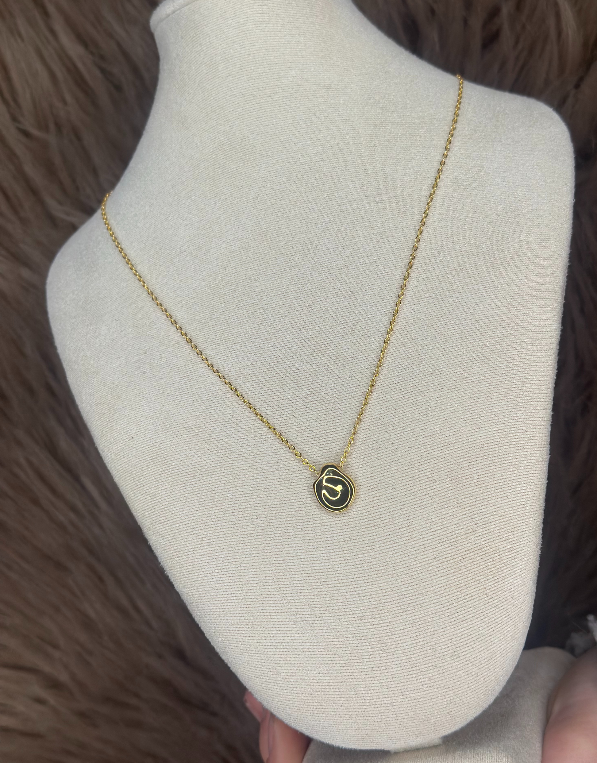 Smuk guld halskæde med abstrakt vedhæng.