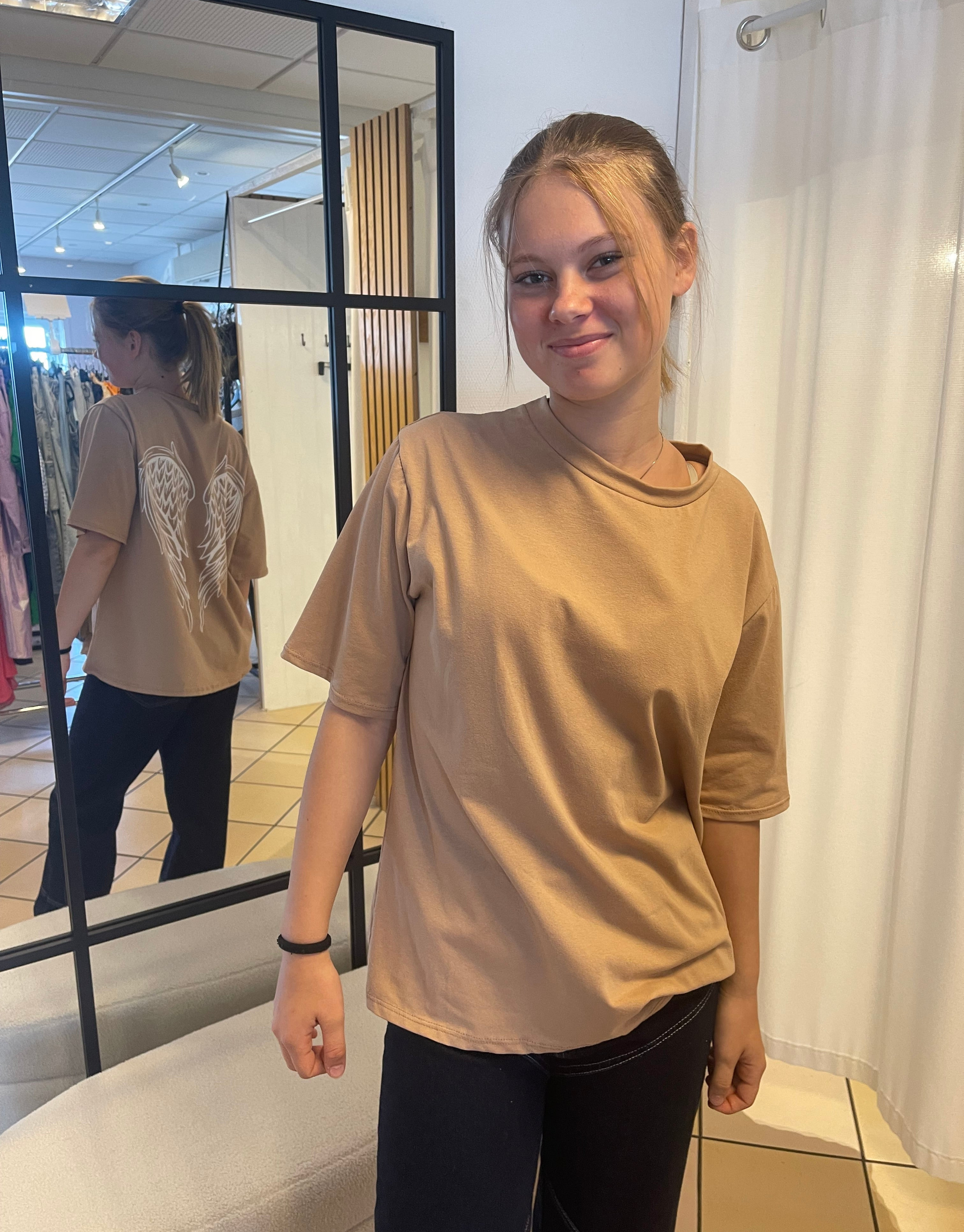 Oversized t-shirt i en flot mørk beige med vinge design på ryggen.
