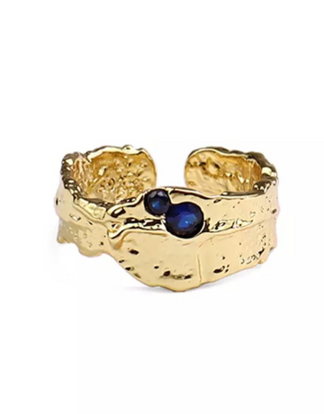 Avelina ring i guld med smukke mørkeblå sten.  Denne smukke ring, er til dig som elsker, at spice dit look op med unikke og deltaljerede smykker. Ringen kan sammensættes med vores andre ringe, for et mere råt look eller bruges alene for et mere enkelt og feminint look.   Overfladen er legeret med 14 karat guld og er meget slidstærk.  Materiale: 70% S925 sterling sølv, 30% rustfri stål, guldbelagt, nikkelfri Størrelse: Justerbar