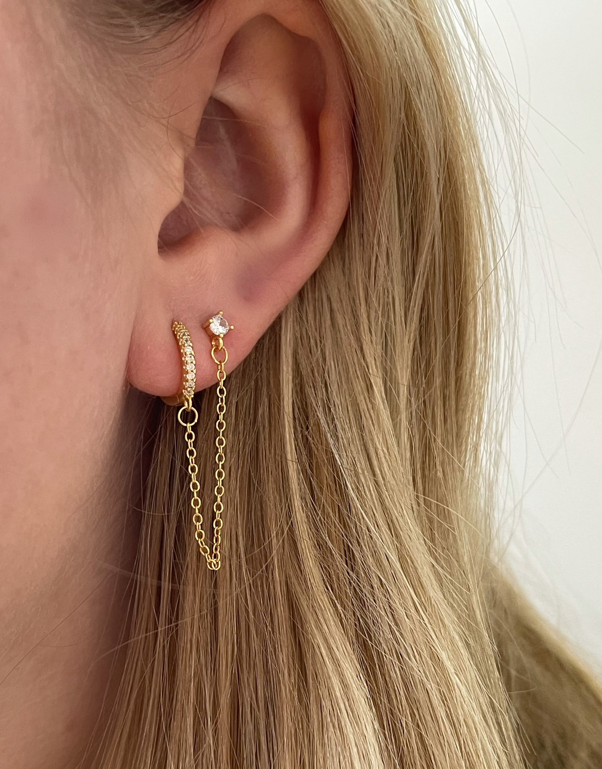 Bella øreringe i guld med vedhæng til ekstra hul i øret. Øreringene er med zircon sten på begge øreringe.   Øreringene er lette og føle behagelige i ørene.