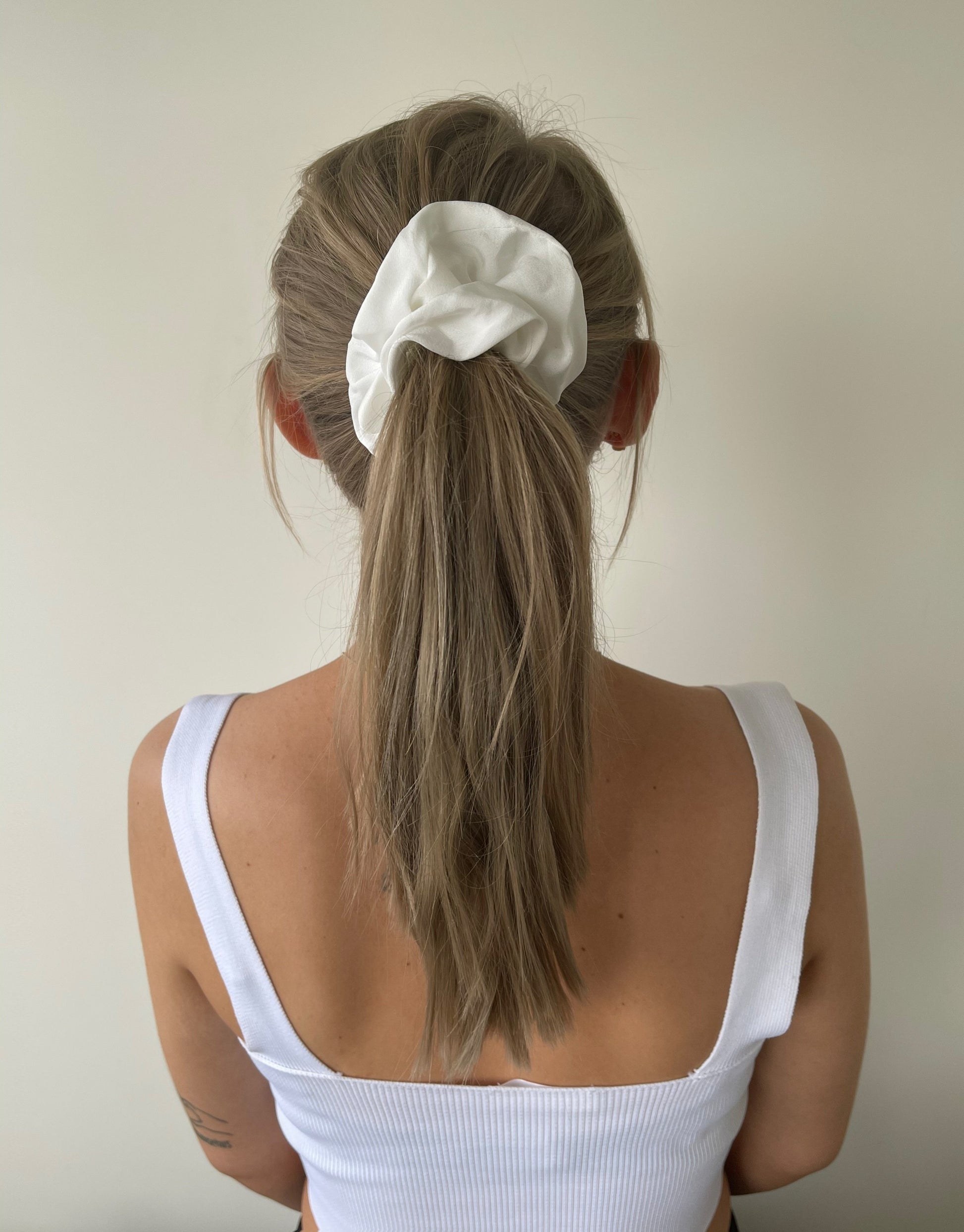 Hvid scrunchie i satin  Disse scrunchies er rigtig gode til at holde på håret og nemme at style med. De er elastiske og har stofbetræk, og kan fås i flere forskellige farver.
