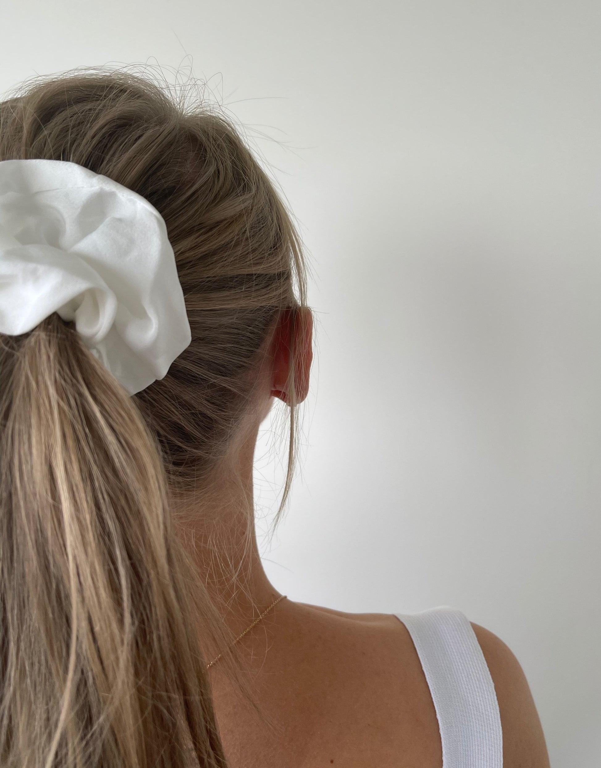 Hvid scrunchie i satin  Disse scrunchies er rigtig gode til at holde på håret og nemme at style med. De er elastiske og har stofbetræk, og kan fås i flere forskellige farver.